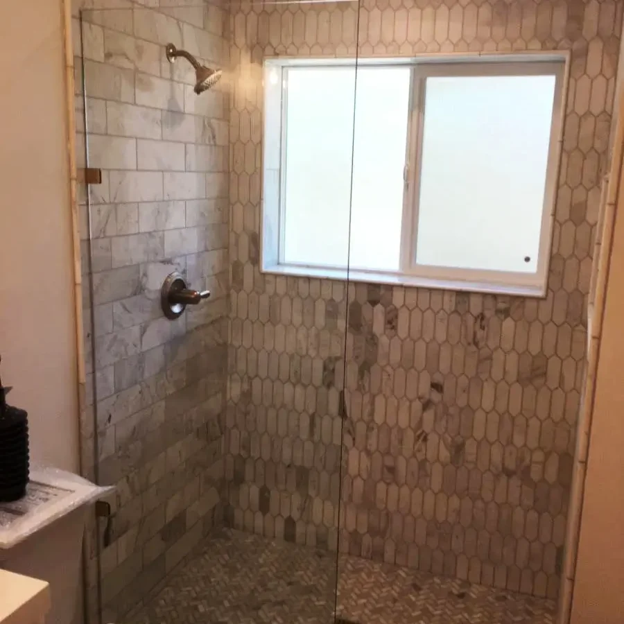Interior of a modern walk-in shower with tile backsplash.