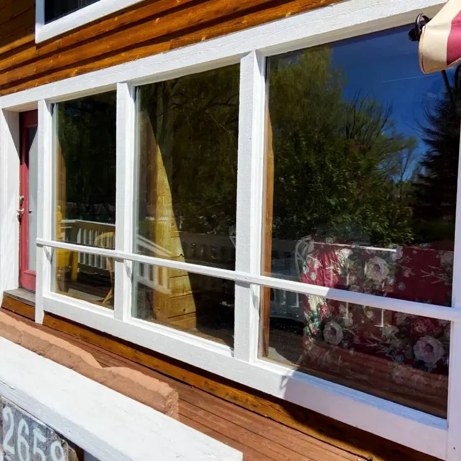 Close up of residential windows during the day. The home has wood siding.